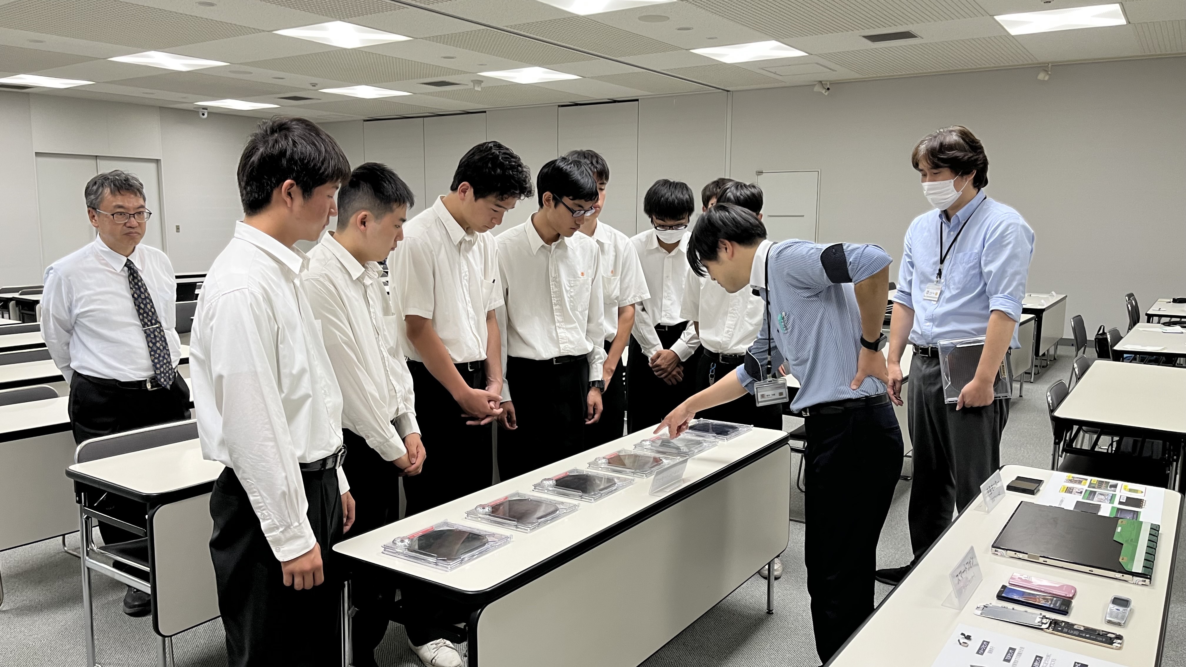 展示されている半導体ウエハについて従業員から説明を受けている生徒たち
